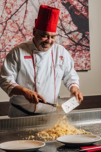 a smiling Benihana chef cooking.