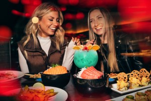 Two women enjoying a meal and sharing a large exotic blue cocktail